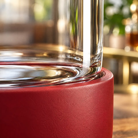 Gros plan sur la jonction du socle rouge mat et de la paroi transparente de la bouteille en verre à bouchon bois Manchon