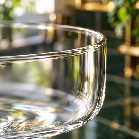 Gros plan en contre-jour sur le buvant fin et la paroi lisse du verre à cocktail Semplice, fond blanc lumineux