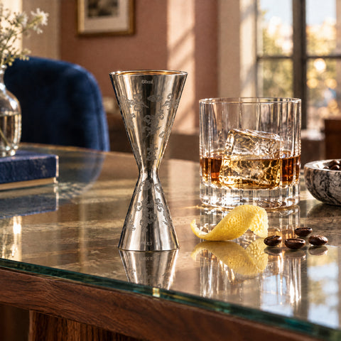 Doseur Fougère debout sur son grand cône, petit cône plein de whisky, zeste de citron et grains de café à côté