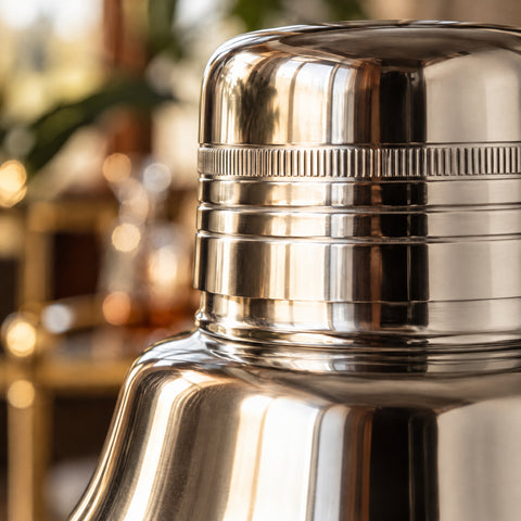 Gros plan sur le moletage vertical du bouchon du shaker Amande en lumière rasante, près du col en inox poli miroir