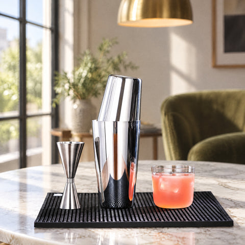 Shaker Gigogne assemblé, doseur double et verre bas de cocktail rose avec glaçon, tapis noir et suspension en laiton