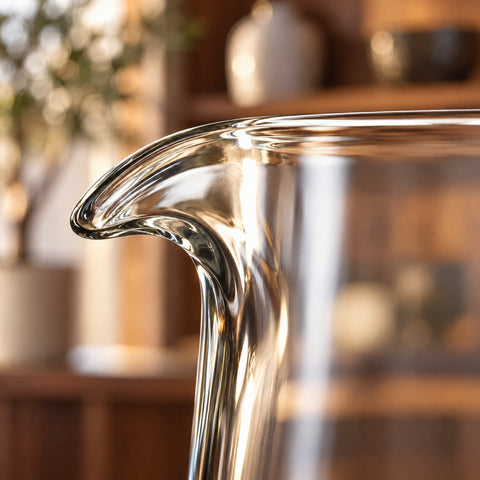 Gros plan en contre-jour sur le bec verseur pincé du verre à mélange à pied Balustre, buvant fin et lisse sur fond blanc