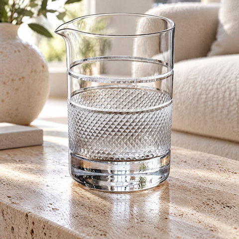 Verre à mélange Jonc rempli d'un liquide limpide jusqu'aux filets gravés, canapé bouclette et vase en céramique