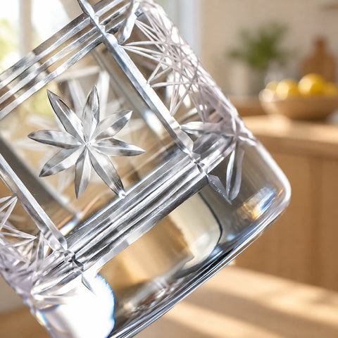 Gros plan incliné sur l'étoile à huit branches du verre à mélange Boussole, bandes de fines lignes, base épaisse, comptoir et citrons flous