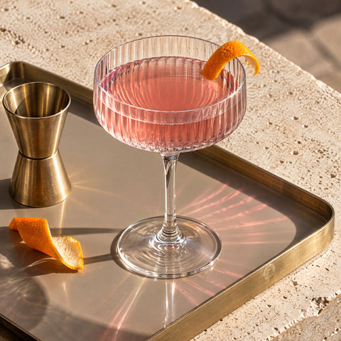 Verre coupe à cocktail Pivoine sur un plateau taupe et laiton, vu d'en haut