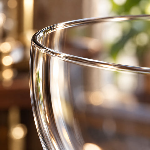 Gros plan sur le buvant fin sans bourrelet du verre Nick and Nora Charleston, paroi lisse en contre-jour sur fond blanc