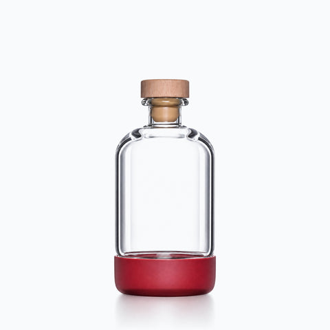 Bouteille verre bouchon bois cylindrique transparente avec socle coloré mat, sur fond clair