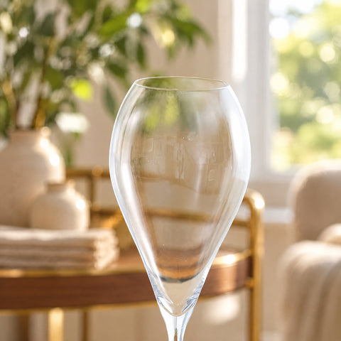 Gros plan sur le buvant fin et le calice tulipe de la flûte à champagne Navette, desserte en noyer et laiton floue