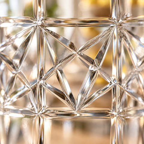 Gros plan rétroéclairé de la bande taillée du verre highball Croisillon, facettes étoilées aux sillons en V lumineux