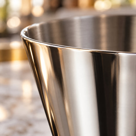 Gros plan sur le bord fin du cône supérieur du doseur Arête, inox poli miroir aux reflets clairs et sombres