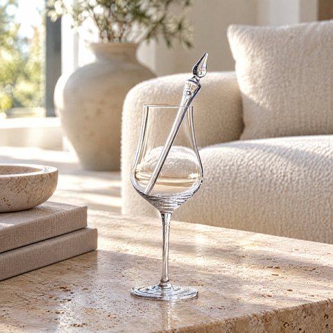 Pipette à eau pour whisky Larme posée en diagonale dans un verre à dégustation tulipe, canapé crème et vase en céramique