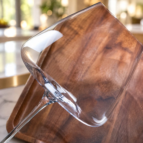 Gros plan sur le buvant fin et la jonction du calice avec la jambe du verre à vin Flèche incliné sur une planche en noyer