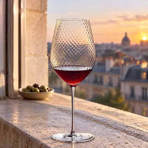 Verre à vin Ténor avec du vin rouge, sur un rebord de fenêtre face aux toits de la ville, coupelle d'olives