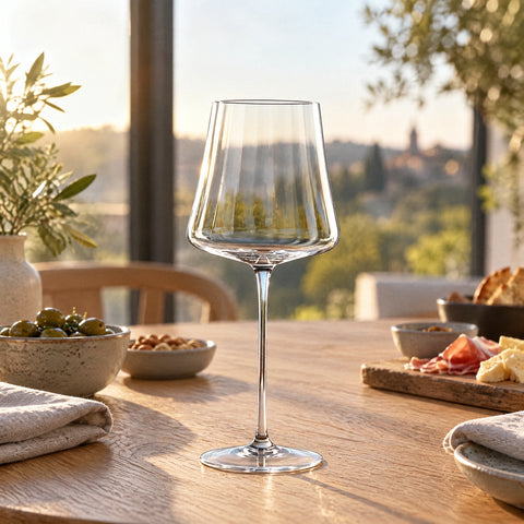 Verre à vin Partition posé seul sur une table d'apéritif près d'une fenêtre, serviettes en lin et coupelles en céramique