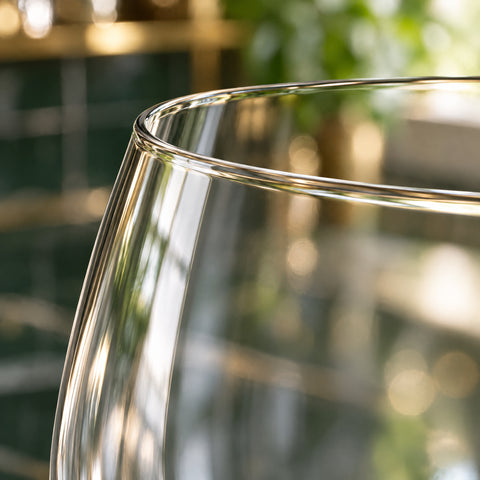 Gros plan sur le buvant fin du verre ballon à gin Bourgeon, en contre-jour sur fond blanc, paroi lisse juste en dessous